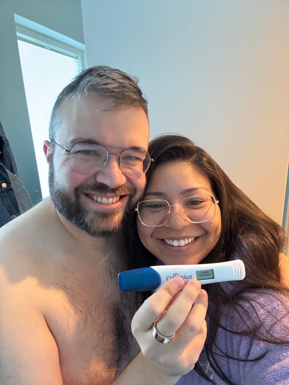 Gen and Daryl in the hallway of their house, holding a positive pregnancy test